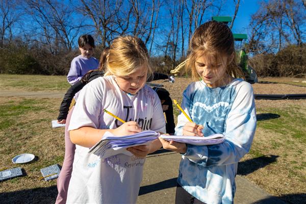 two students writing in notebook